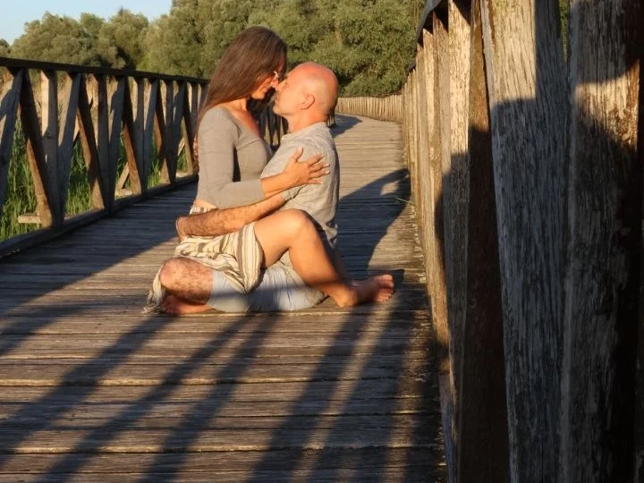 A couple in a gentle embrace on a wooden bridge